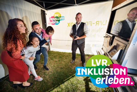 Fotograf mit Fotoa&uuml;pparat auf Stativ. Menschen lassen sich fotografieren