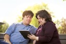 Zwei Menschen mit Behinderungen schauen auf ein Tablet