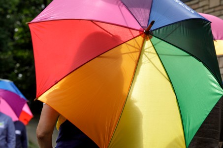 Man sieht einen Regenschirm in Regenbogenfarben.