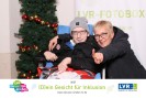 Junger Mann im Rollstuhl, Frau nimmt ihn in den Arm, beide stehen vor Weihnachtsdeko, beide l&auml;cheln