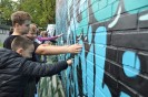 Man sieht junge Menschen vor einer Wand mit Graffiti