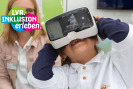 Ein Kind lächelt, hat eine VR-Brille auf und schaut nach oben. Oben links befindet sich das Logo "LVR. Inlusion erleben."