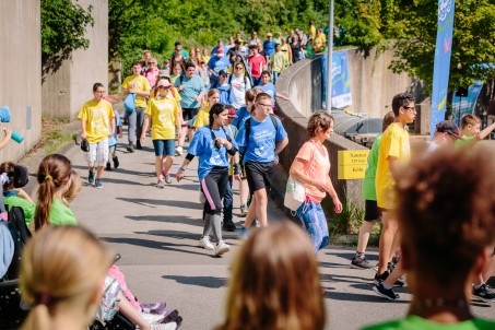 Eine Gruppe von Jugendlichen l&auml;uft eine Stra&szlig;e entlang. Die meisten tragen blaue oder gelbe T-Shirts.